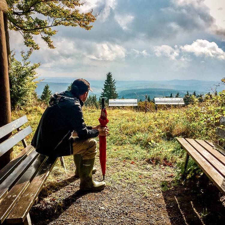 Mann sitzt mit Schirm in der Schutzhütte am Kalied