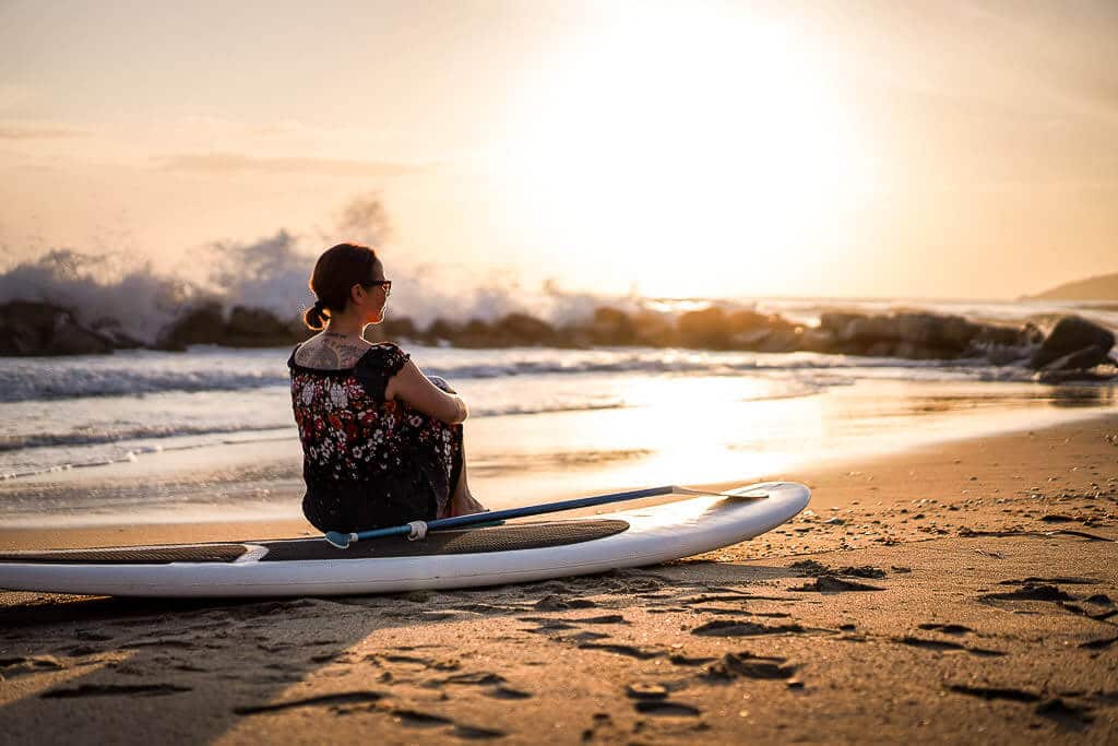 Couchflucht Sabrina Bechtold sitzt auf SUP am Strand von Casal Velino