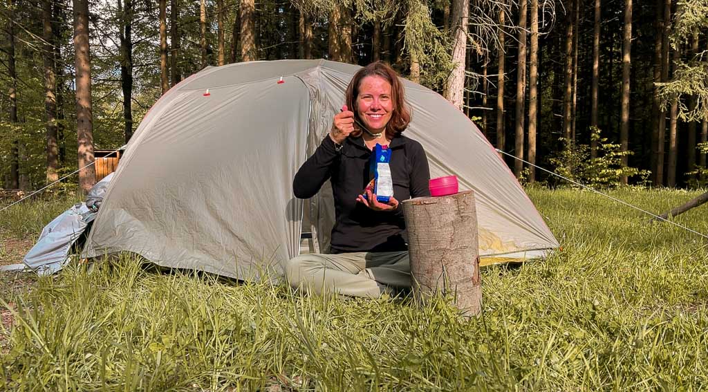 Couchflucht Sabrina Bechtold isst Trekkingessen vor dem Zelt auf dem Trekkingplatz Rehwiese im Frankenwald.
