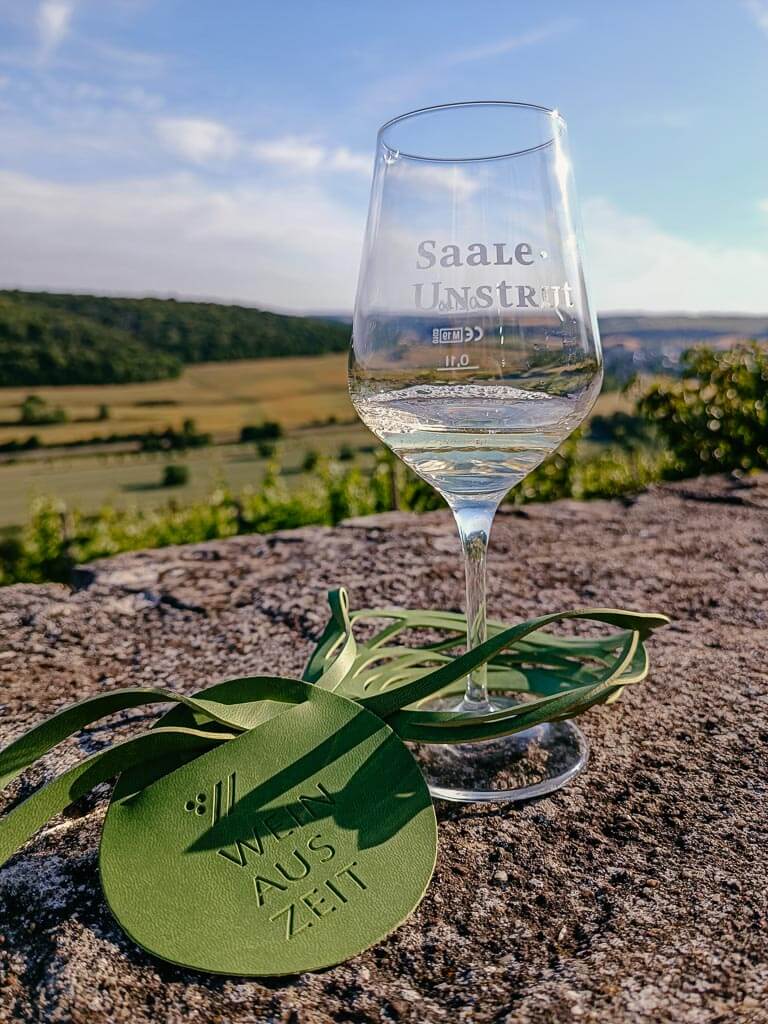 Weinglas mit Ausblick ins Unstruttal auf der Weinwanderung mit Weinauszeit